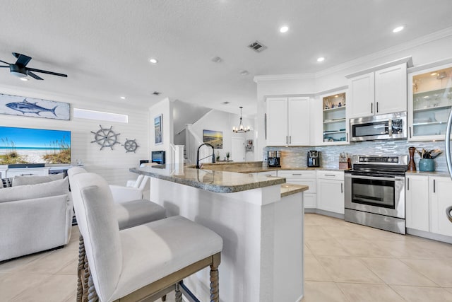 kitchen featuring stainless steel appliances, a breakfast bar, visible vents, open floor plan, and glass insert cabinets