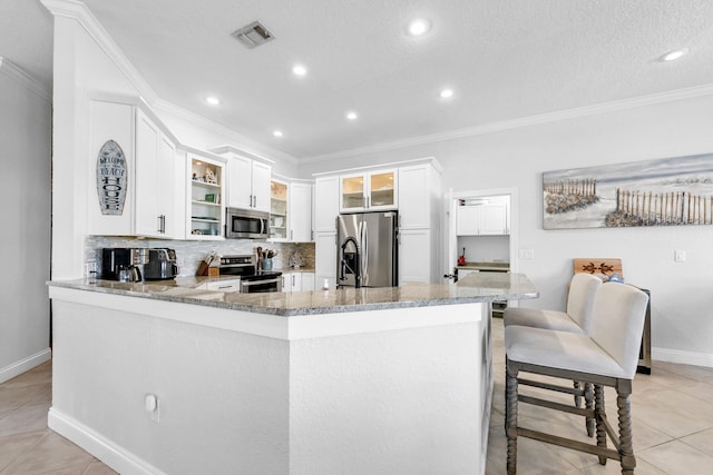 kitchen with visible vents, light stone counters, stainless steel appliances, crown molding, and backsplash