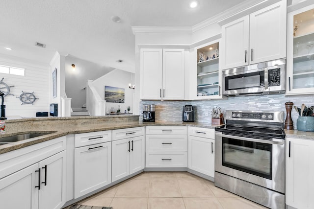 kitchen featuring light tile patterned floors, decorative backsplash, light stone countertops, stainless steel appliances, and white cabinetry