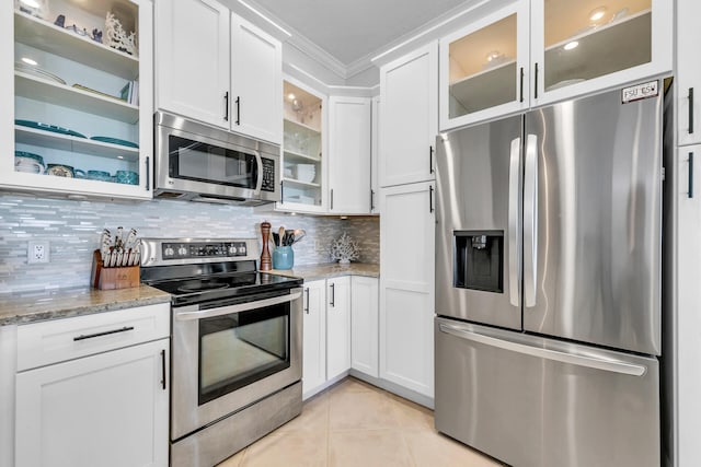 kitchen with light tile patterned floors, tasteful backsplash, appliances with stainless steel finishes, glass insert cabinets, and ornamental molding