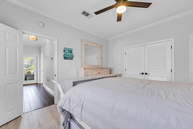 bedroom with light wood finished floors, a closet, visible vents, ornamental molding, and a ceiling fan