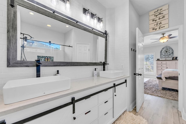 ensuite bathroom with double vanity, a sink, ensuite bathroom, and wood finished floors