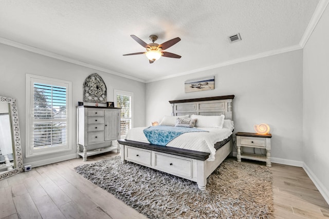 bedroom featuring visible vents, ornamental molding, a textured ceiling, wood finished floors, and baseboards