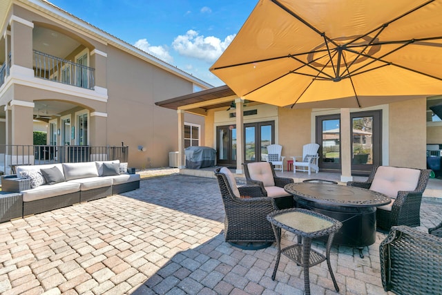 view of patio / terrace featuring a balcony, ceiling fan, an outdoor living space, and french doors