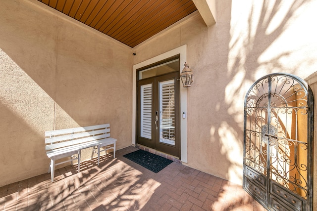 view of exterior entry featuring french doors and stucco siding