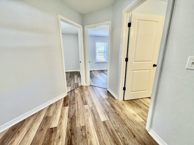 hall with light wood-type flooring and baseboards