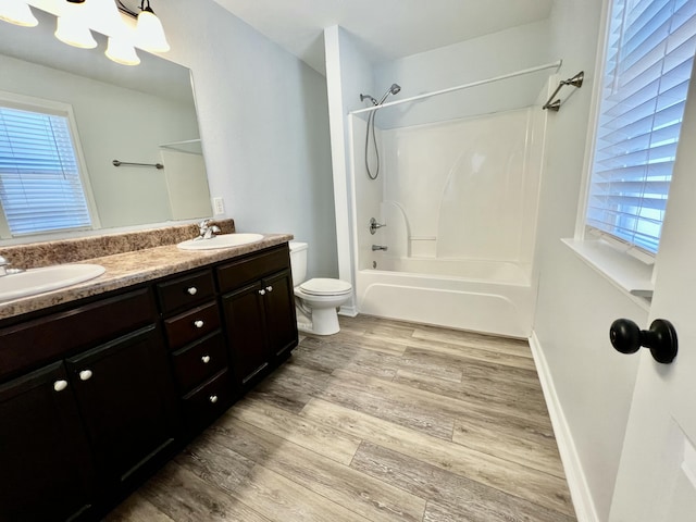 full bathroom with shower / bath combination, double vanity, toilet, wood finished floors, and a sink