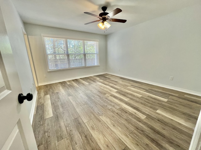 empty room with light wood finished floors, a ceiling fan, and baseboards