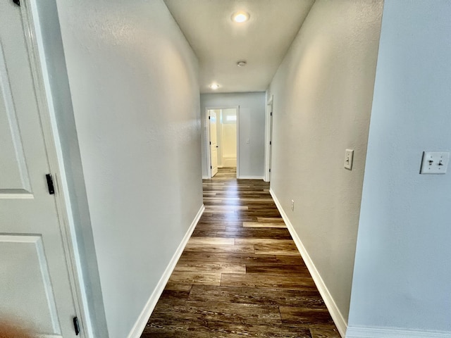 hallway featuring dark wood-style floors and baseboards