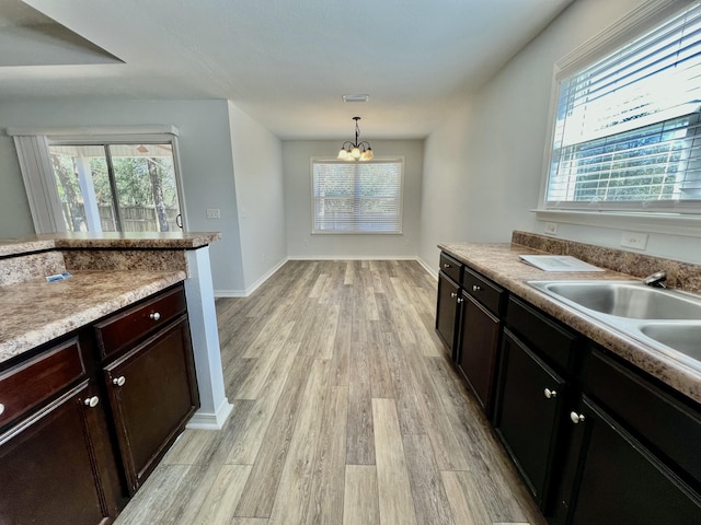 kitchen with decorative light fixtures, light countertops, light wood-style floors, a sink, and plenty of natural light