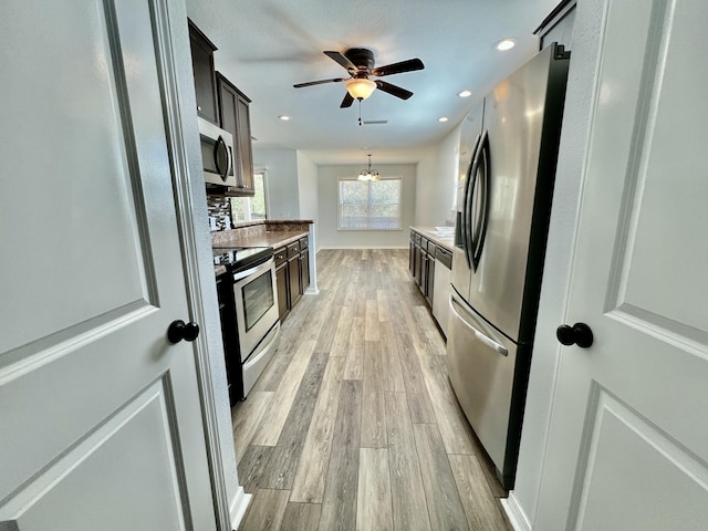 kitchen featuring recessed lighting, ceiling fan with notable chandelier, light countertops, appliances with stainless steel finishes, and light wood-type flooring