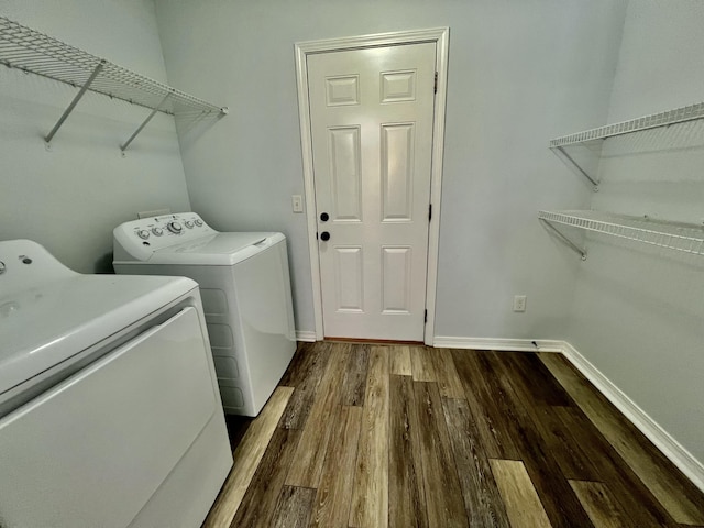 washroom featuring washer and dryer, laundry area, baseboards, and wood finished floors