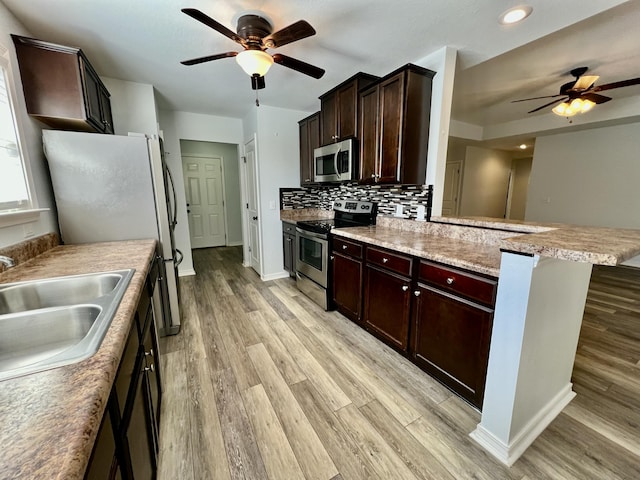 kitchen with a sink, light countertops, appliances with stainless steel finishes, backsplash, and a kitchen bar