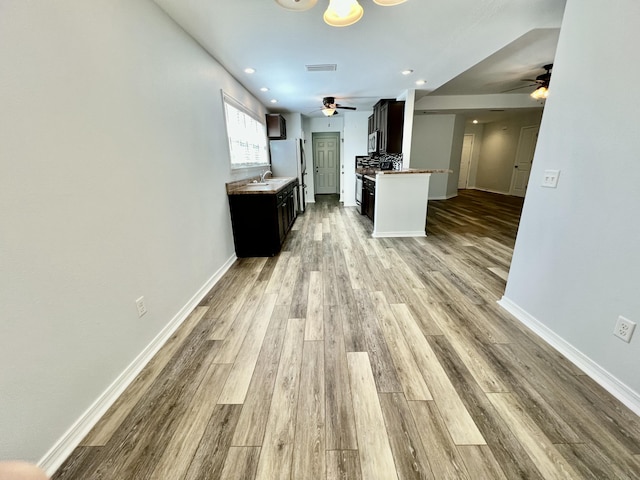 kitchen with light wood finished floors, baseboards, stainless steel appliances, and recessed lighting