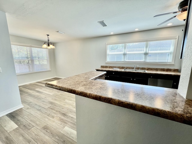 kitchen with a wealth of natural light, wood finished floors, visible vents, and decorative light fixtures