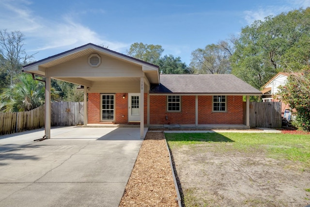 view of front of house featuring driveway, fence, a carport, and brick siding