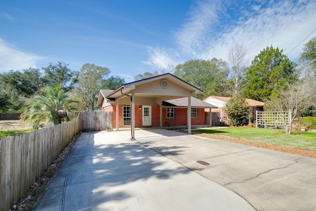 view of front facade with driveway, fence, a front lawn, and brick siding