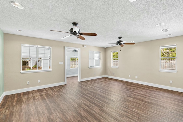 unfurnished room featuring a textured ceiling, dark wood finished floors, visible vents, and baseboards