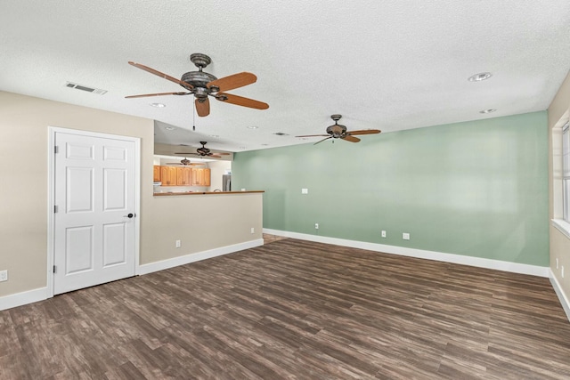 unfurnished living room featuring baseboards, a textured ceiling, visible vents, and dark wood-type flooring