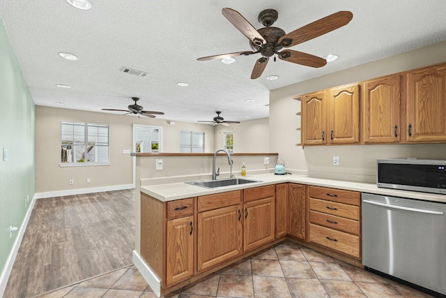 kitchen with a peninsula, appliances with stainless steel finishes, light countertops, and a sink