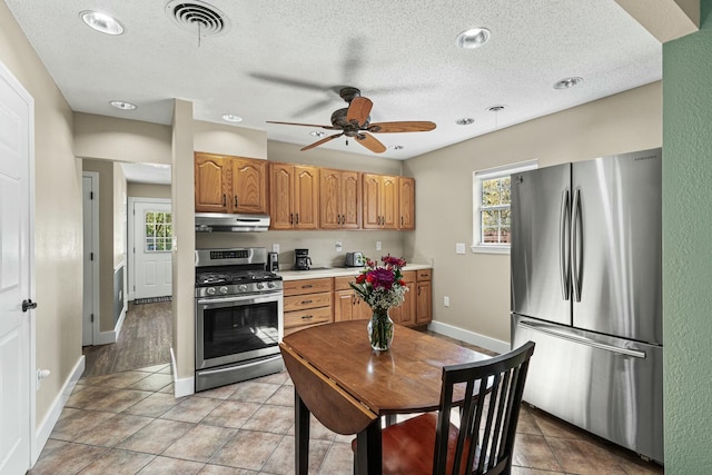 kitchen with under cabinet range hood, visible vents, light countertops, appliances with stainless steel finishes, and a wealth of natural light