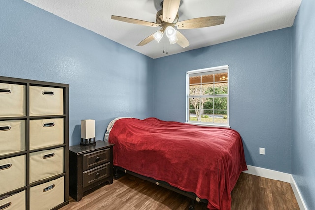 bedroom with ceiling fan, a textured wall, wood finished floors, and baseboards