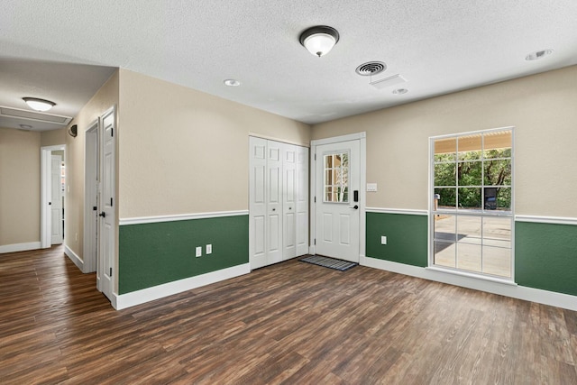 unfurnished room with dark wood-style floors, visible vents, a textured ceiling, and baseboards