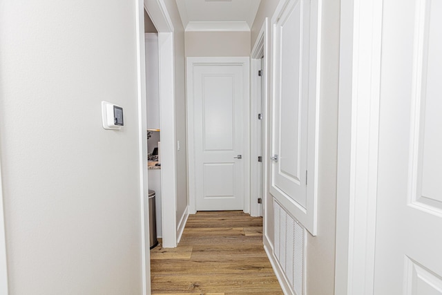 hallway featuring light wood-type flooring and crown molding