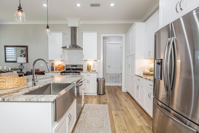 kitchen with wall chimney exhaust hood, stainless steel appliances, decorative light fixtures, crown molding, and white cabinetry