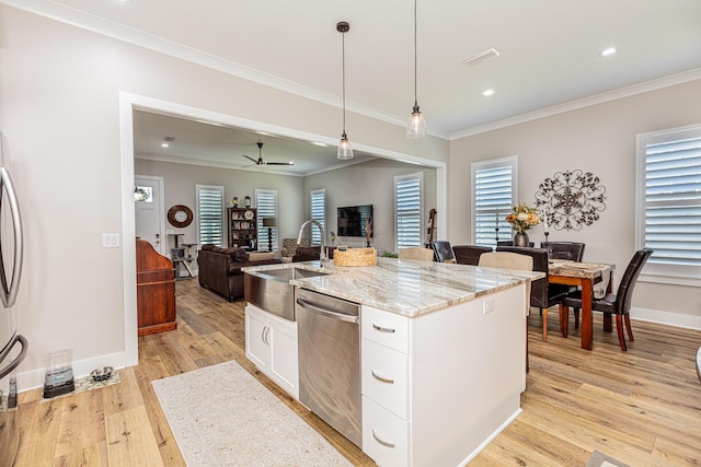 kitchen featuring sink, pendant lighting, stainless steel appliances, white cabinets, and a kitchen island with sink