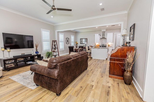 living room featuring ornamental molding, light hardwood / wood-style flooring, sink, and ceiling fan