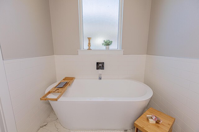 bathroom featuring tile walls and a bath