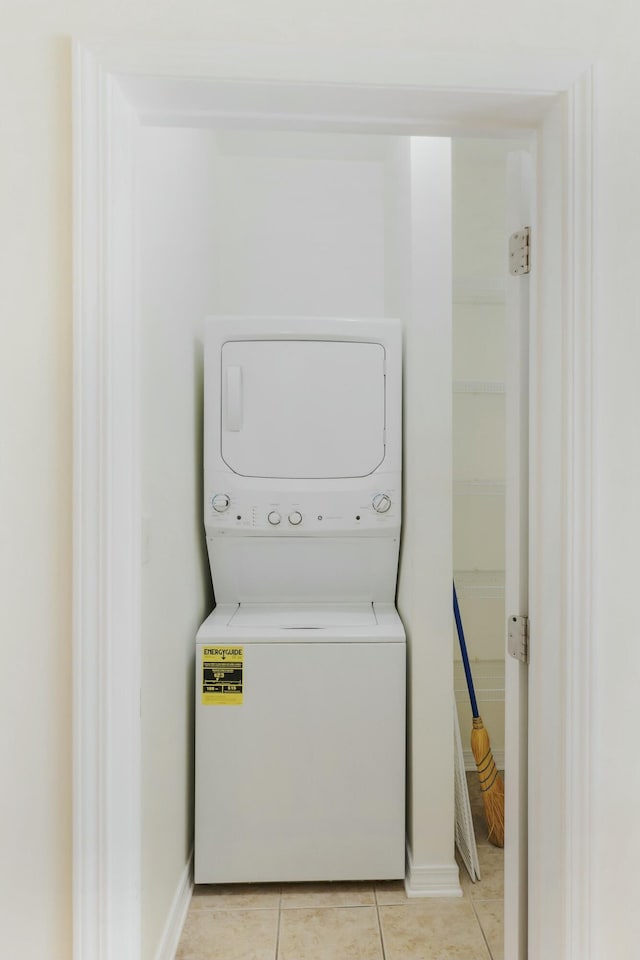 clothes washing area with stacked washing maching and dryer and light tile patterned floors