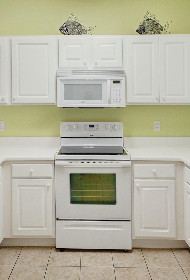 kitchen with white appliances, white cabinetry, and light tile patterned floors