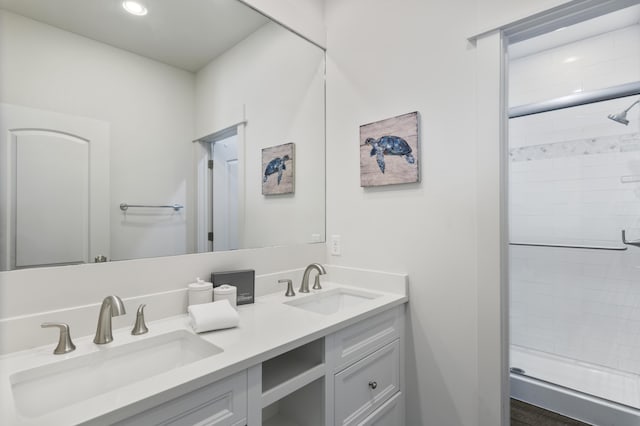 full bathroom featuring double vanity, a stall shower, and a sink