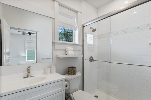 bathroom featuring toilet, a shower stall, ceiling fan, and vanity