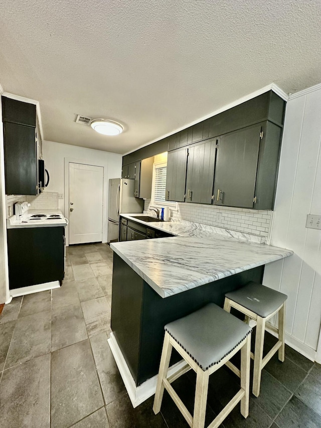 kitchen featuring appliances with stainless steel finishes, tasteful backsplash, a breakfast bar area, sink, and kitchen peninsula