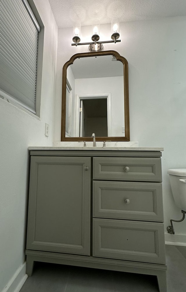 bathroom with a textured ceiling, toilet, and vanity