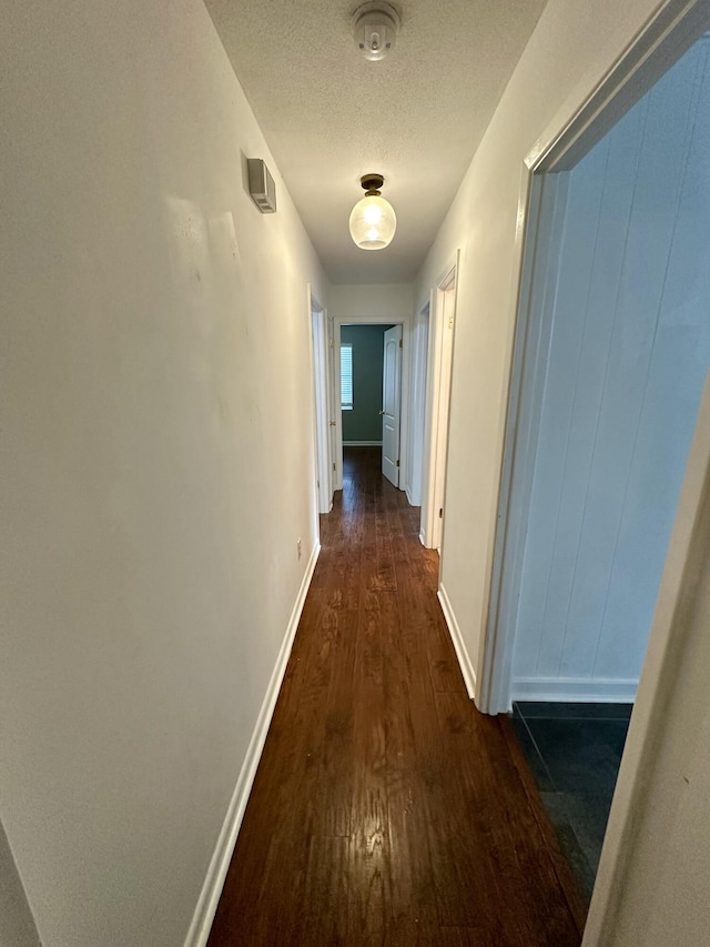 hallway featuring dark hardwood / wood-style flooring and a textured ceiling