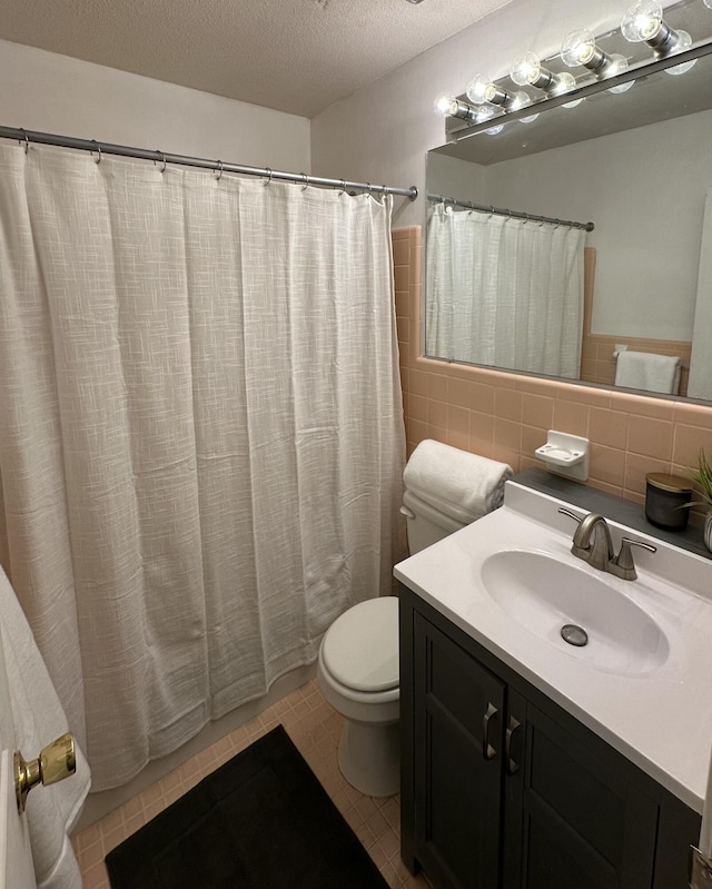 bathroom with a shower with curtain, toilet, tile walls, a textured ceiling, and vanity