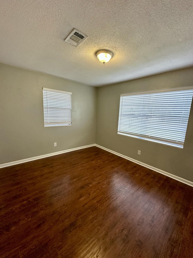 unfurnished room featuring a textured ceiling and dark wood-type flooring