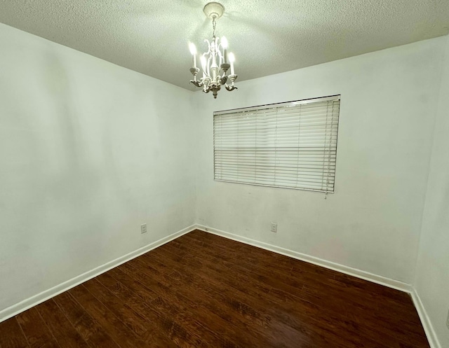 unfurnished room featuring a notable chandelier, dark hardwood / wood-style floors, and a textured ceiling