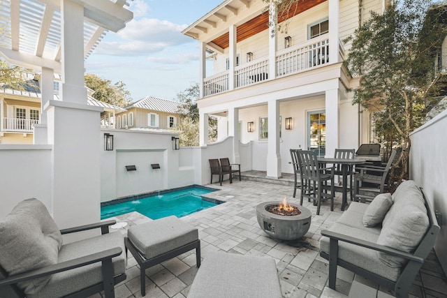 exterior space featuring an outdoor pool, an outdoor living space with a fire pit, a balcony, fence, and outdoor dining space