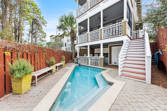 back of property featuring a ceiling fan, a fenced backyard, stairway, and a fenced in pool