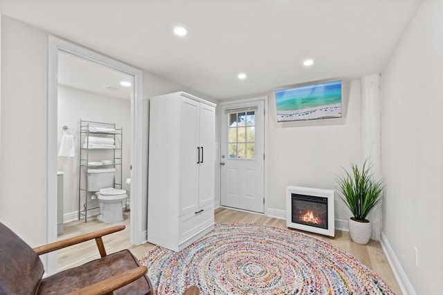 entryway featuring recessed lighting, light wood-style flooring, baseboards, and a glass covered fireplace