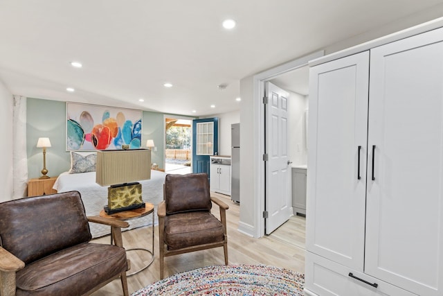 bedroom with light wood-style floors, recessed lighting, and stainless steel fridge