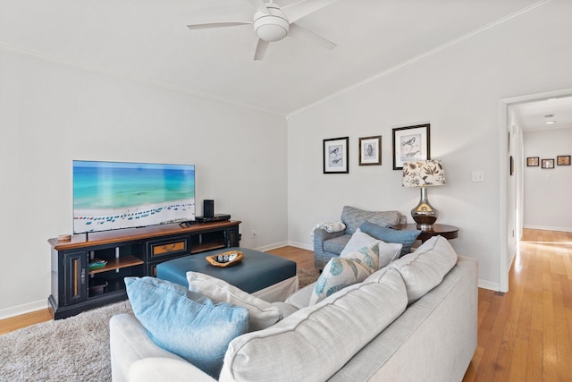 living area with crown molding, light wood-style flooring, vaulted ceiling, ceiling fan, and baseboards