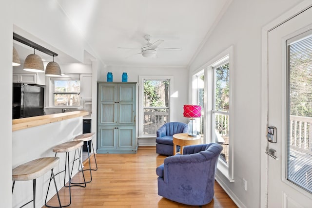 sitting room with light wood-style floors, a wealth of natural light, crown molding, and a ceiling fan