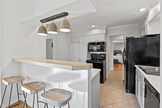 kitchen featuring a peninsula, a kitchen breakfast bar, white cabinets, black appliances, and pendant lighting