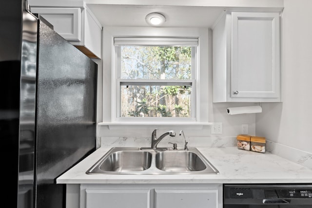 kitchen featuring black appliances, light stone counters, a sink, and white cabinets